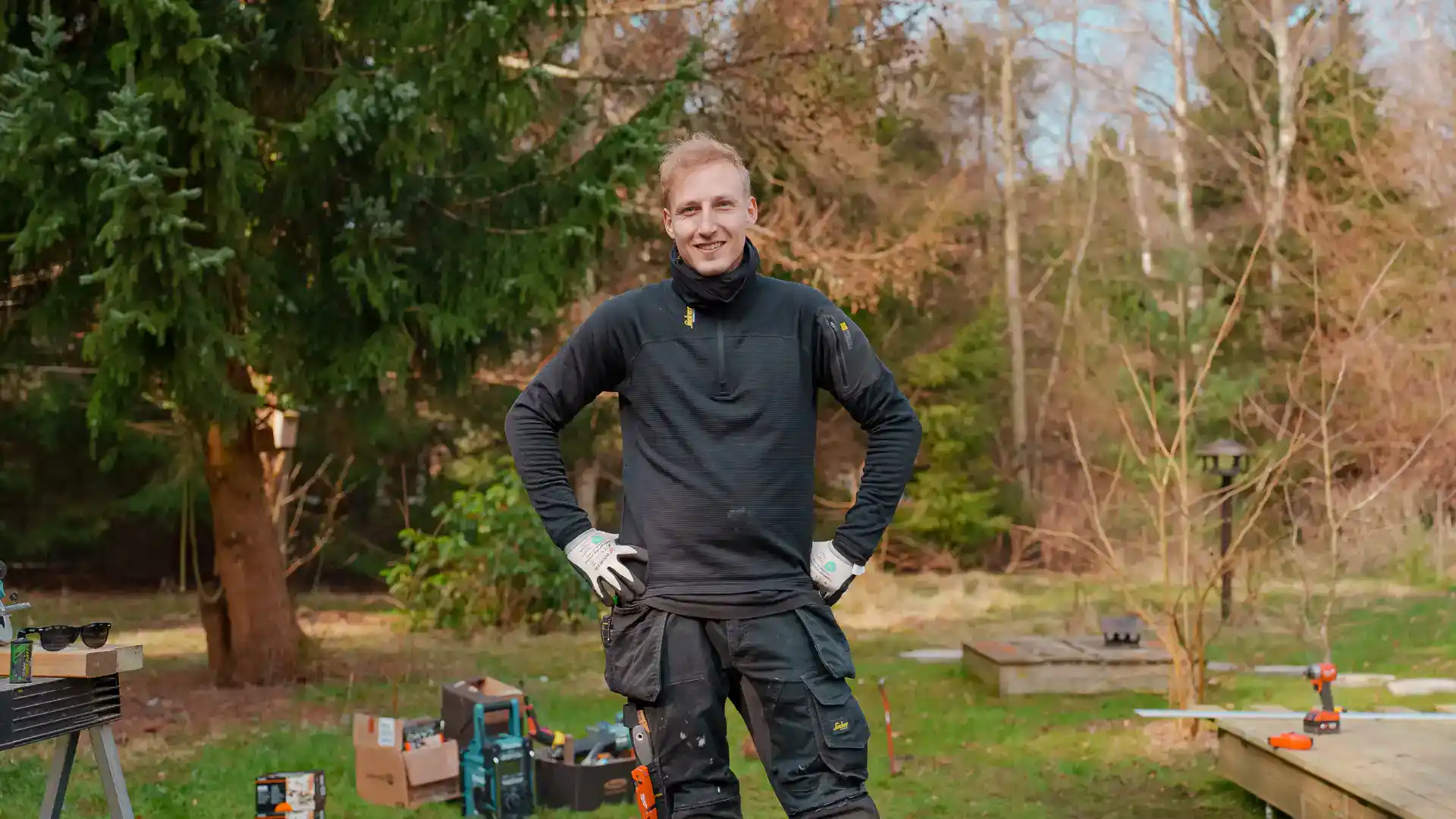 Mand står med værktøj i skovområde, klar til træarbejde.