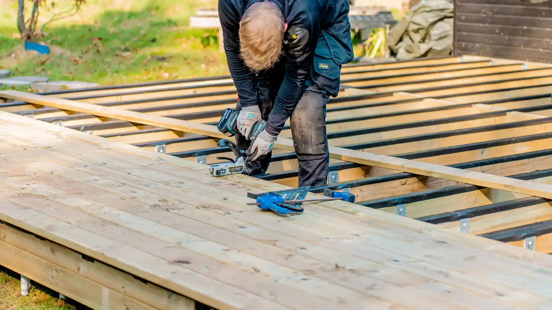 Mand bygger træterrasse med værktøj i hånden.