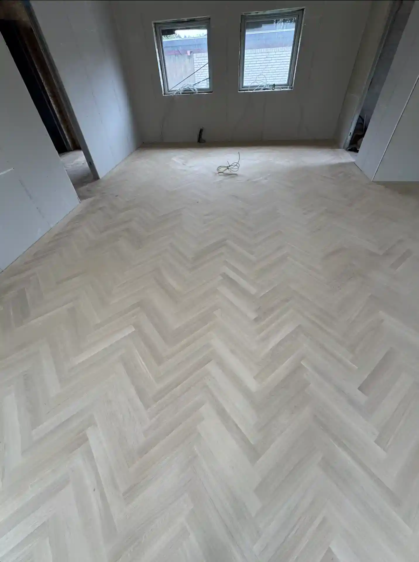 Nyrenoveret værelse med elegant, lyst trægulv i herringbone-mønster.